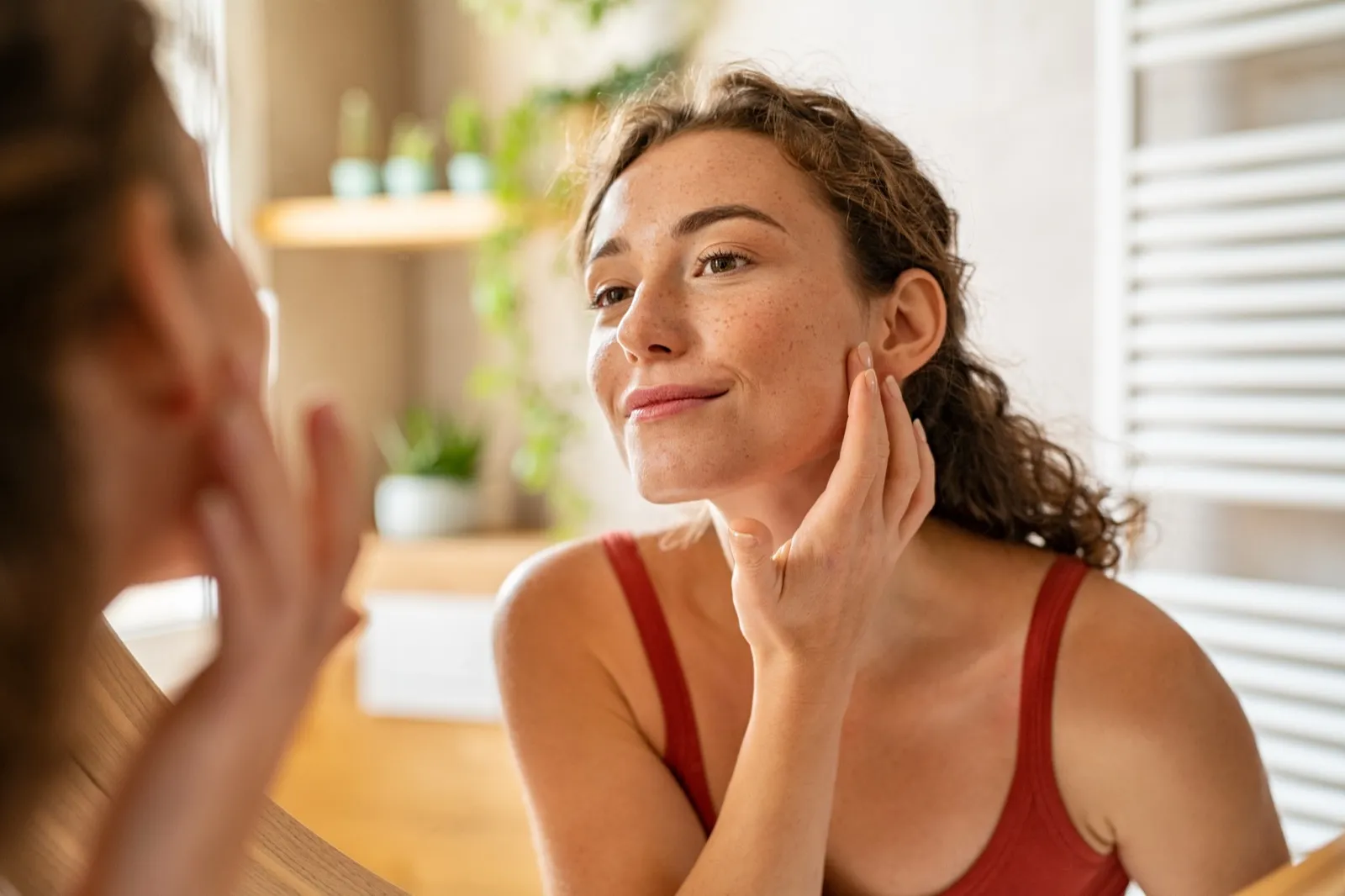 Woman checking her skin in the mirror, calm morning light